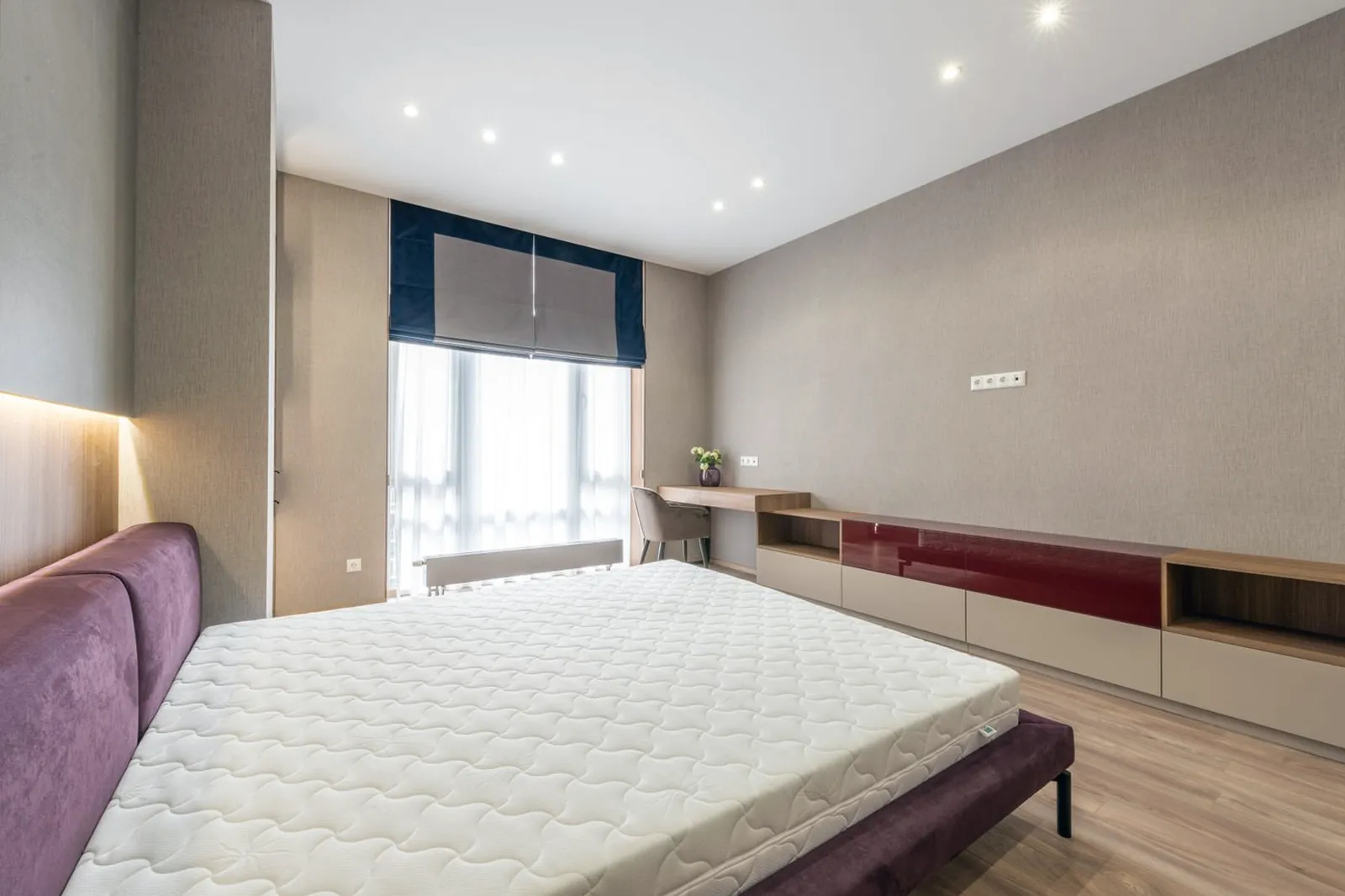 Matelas nu posé sur son cadre de lit dans une chambre lumineuse, coutures apparentes